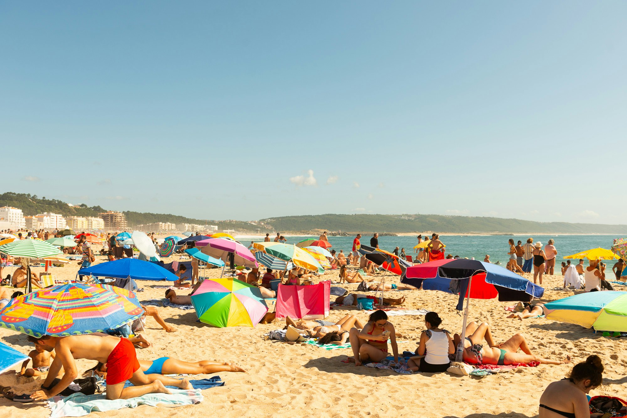 Umbrellas and sunbathers on the beach in Nazaré, Portugal